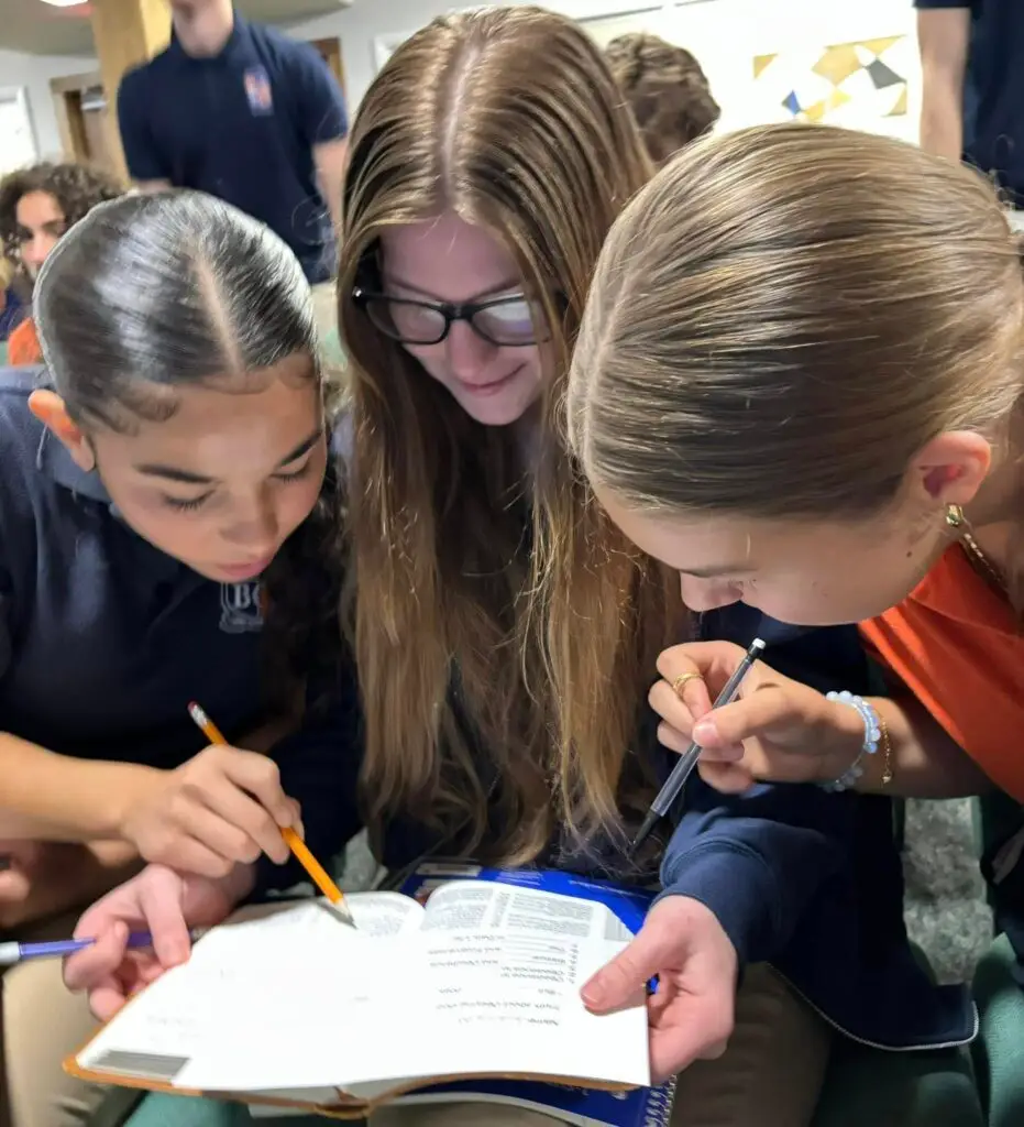 Three students at Bethany Christian School study the Bible together during a chapel activity.