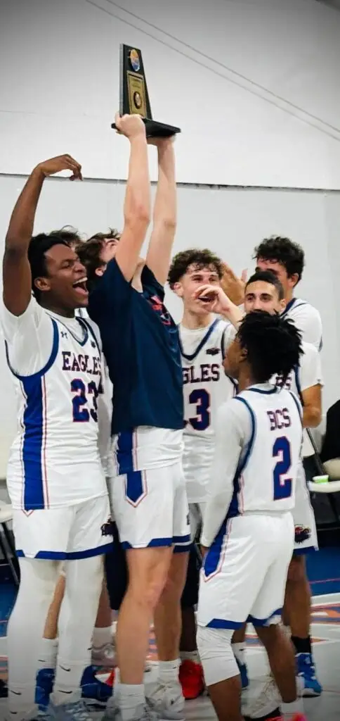 BCS boys basketball team celebrating championship win, holding up tournament trophy