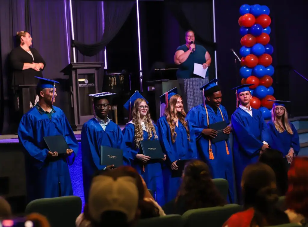BCS high school graduates in blue caps and gowns celebrating commencement
