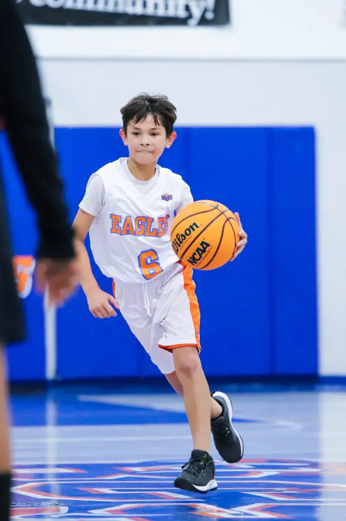 Young BCS basketball player dribbles down the court with focus