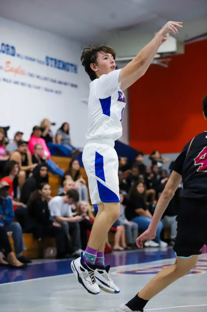 BCS middle school basketball player shoots a three-pointer as crowd watches