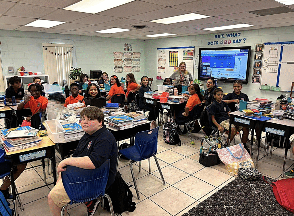 Fifth grade students at Bethany Christian School smile and engage in a vibrant classroom setting, surrounded by books and resources.