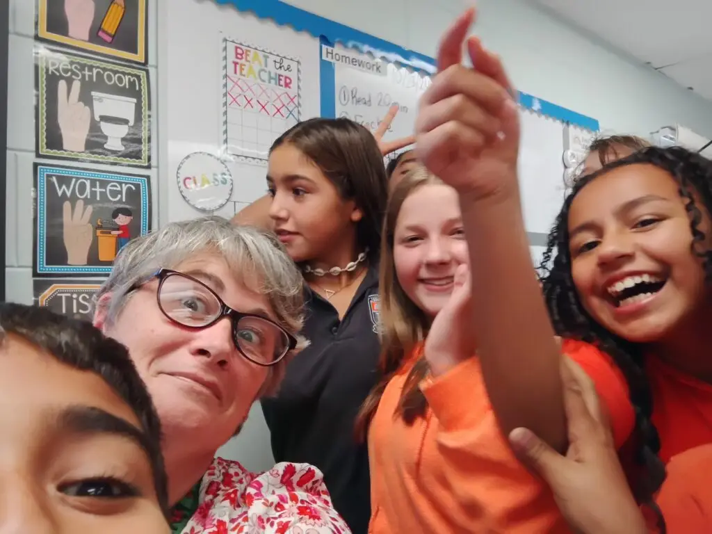 Bethany Christian School elementary teacher smiling with students during classroom activity, showing joyful learning environment.