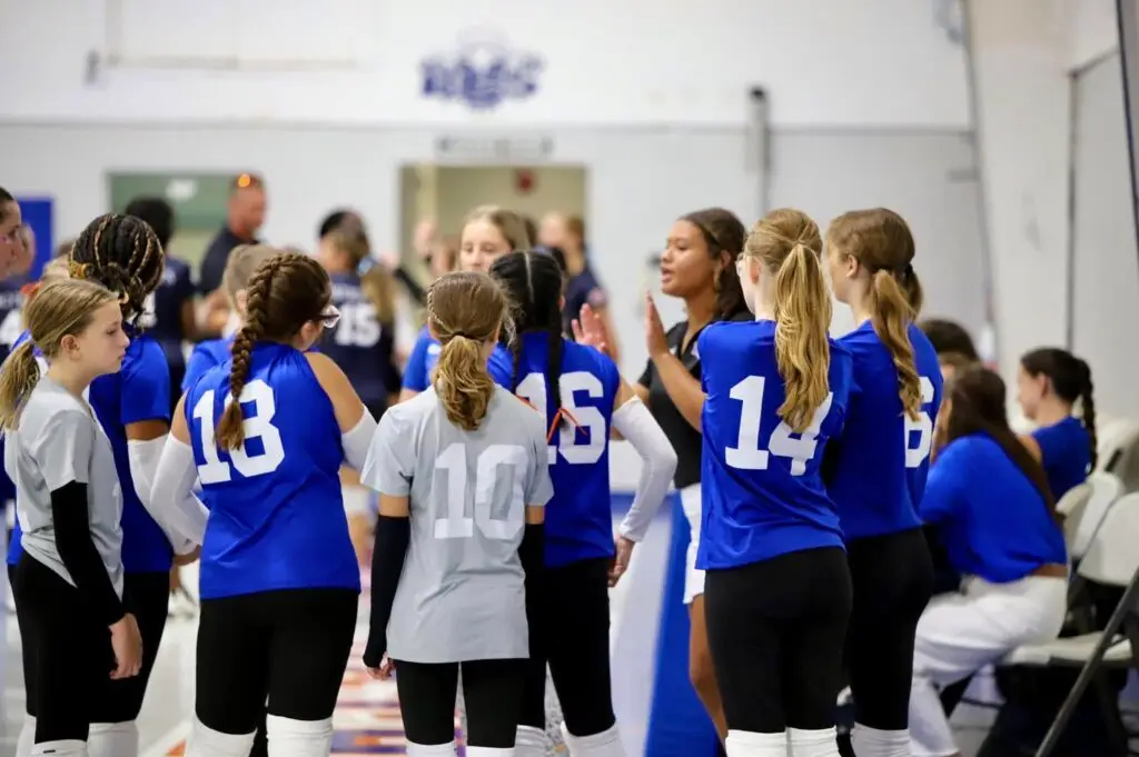 Bethany Christian School middle school volleyball team huddling during game, demonstrating teamwork, responsibility, and cooperation.